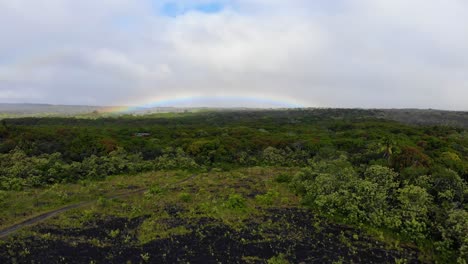 Slow-ascent-over-road-and-forest-and-lava-fields-with-rainbow-in-the-bacgkround