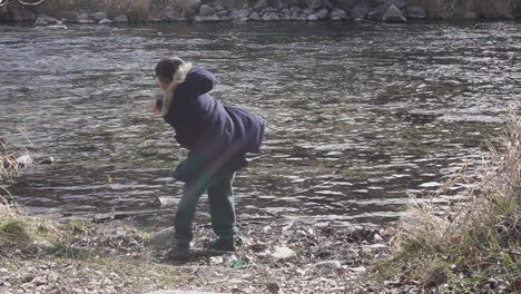 Kid-throwing-sticks-in-a-river-in-winter