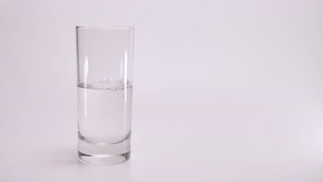 Un-Vaso-Transparente-Está-Lleno-De-Agua-Limpia-Sobre-Un-Fondo-Blanco