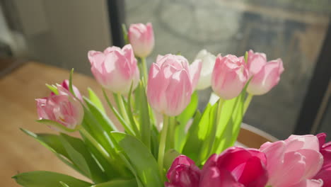 Backlit-tulips-sway-gently-in-a-vase-on-a-sunny-day,-close-up-with-a-dolly-out-motion