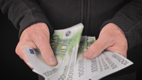 A-man-receives-and-counts-100-euro-bills-with-his-hands