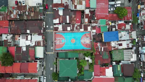 Top-down-aerial-establishing-shot-of-urban-basketball-court-in-third-world-Asian-country-with-dilapidated-rooftops