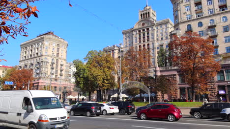 Khreshchatyk-main-street-of-Kyiv-city-capital-in-Ukraine,-sunny-autumn-weather-and-cars-driving,-tall-apartment-buildings,-4K-shot