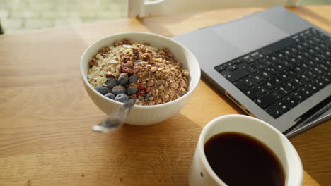 Sunny-wooden-home-office-workspace-with-a-nutritious-breakfast-bowl-and-coffee