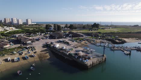 Small-fisher-ship-port-in-Alvor-Portugal,-aerial-orbit-with-skyline-of-the-city