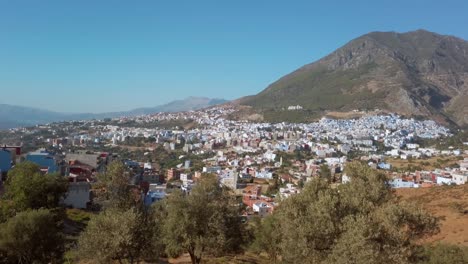 Chefchaouen,-the-Blue-Perl-traditional-city-view-from-a-distance,-surrounded-by-the-Riff-Mountains-on-a-clear-sunny-day-in-Morocco