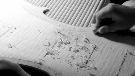 Stringed-instrument-maker-master-luthier-artisan-hand-proceed-with-graduation-work-on-cello-back-plate,-divide-wood-in-areas-to-carve-different-thickness-with-planes,-Wood-chips-and-curls-pile-up
