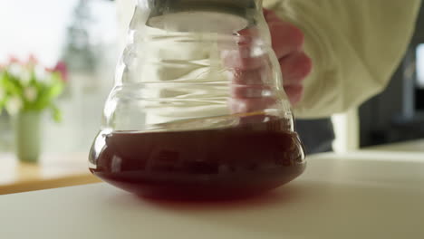 Fresh-coffee-extraction-in-a-clear-glass-jug-on-a-white-table-in-Slow-Motion