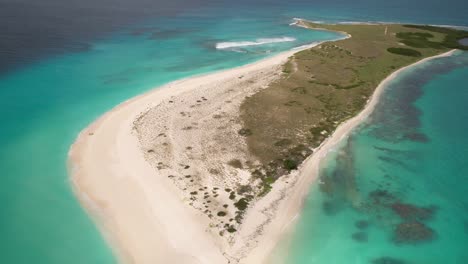 Serene-beach-in-Los-Roques,-Venezuela-with-clear-turquoise-waters-and-a-single-blue-umbrella,-aerial-view,-timelapse