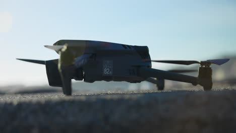 Close-Up-View-Of-DJI-Mavic-3-Pro-On-Ground-With-Lens-Flare-In-Shot