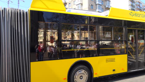 Gelber-Trolleybus-Fährt-Auf-Der-Straße-Im-Sonnigen-Stadtzentrum-Von-Kiew,-Beliebter-Elektrobus-Für-öffentliche-Verkehrsmittel-In-Der-Ukraine,-4K-Aufnahme