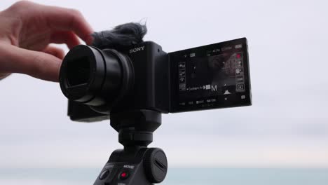 Young-adult-male-adjusting-setting-on-Sony-vlogging-touchscreen-camera
