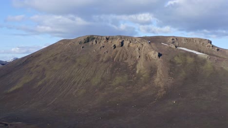 Aerial-drone-view-with-an-orbiting-left-movement,-facing-a-green-and-rhyolite-mountain-in-Landmannalaugar-near-Stutur-Crater