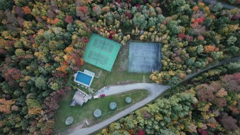 Aerial-Top-View-Of-Fall-Trees-Surrounding-Recreational-Facility-With-Outdoor-Swimming-Pool-And-Tennis-Courts-In-Vermont,-USA