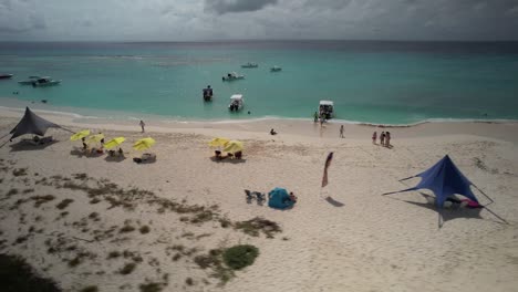 Busy-tropical-beach-on-Los-Roques-archipelago-with-boats-and-visitors,-aerial-view