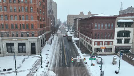 Aerial-establishing-shot-of-a-city-intersection-as-snow-falls
