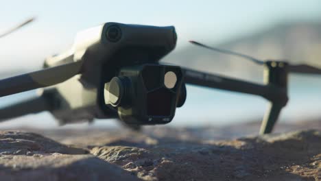 Close-Up-View-Of-DJI-Mavic-3-Pro-Camera-Gimbal-Module-On-Ground-With-Lens-Flare-In-Shot