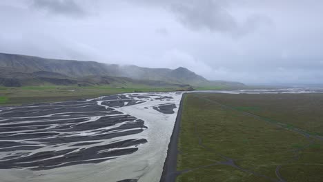 Aerial-view-of-a-braided-river-flowing-towards-the-ocean-on-a-cloudy-day-in-Iceland