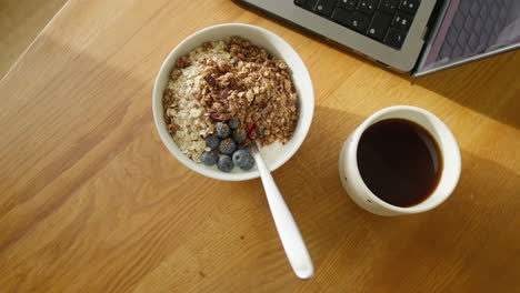 Sunny-wooden-workspace-with-a-nutritious-breakfast-bowl-and-coffee