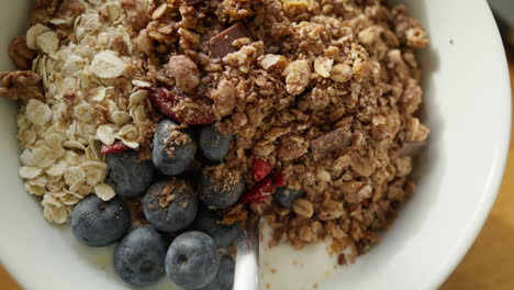 Detailed-view-of-a-nutritious-granola-bowl-with-oats,-chocolate,-and-berries