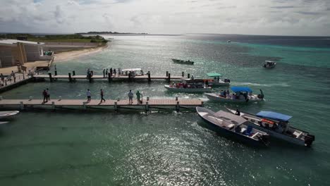 Boats-docked-at-a-pier-in-Los-Roques,-Venezuela-with-clear-turquoise-waters,-aerial-view