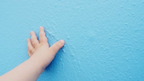 Hand-of-a-baby-touches-blue-wall-with-copy-space,-gender-reveal
