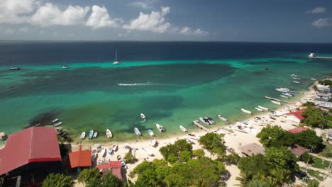 Los-Roques-archipelago-with-crystal-waters,-moored-boats,-and-colorful-buildings,-aerial-view