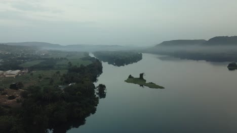 Aerial-shot-of-a-slow-descent-with-a-view-of-the-village-buildings-and-island-on-the-Volta-River