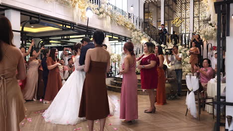 Wedding-guests-throwing-flower-petals-and-blowing-bubbles-at-the-newlyweds-at-a-reception-inside-a-hotel-in-Bangkok,-Thailand