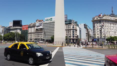 Crowded-Traffic-at-9-de-Julio-Avenue-Center-of-City-Downtown,-Daylight-Obelisk
