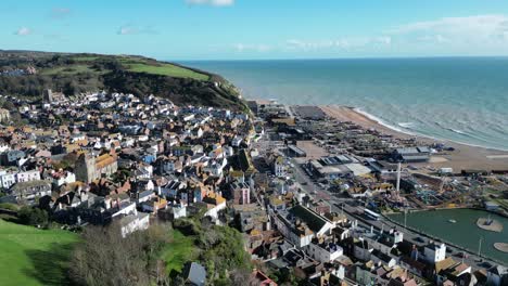 Aerial-drone-shot-of-Hastings-UK,-Orbiting-shot,-flying-over-old-town-looking-towards-town,-ocean-and-East-Hill
