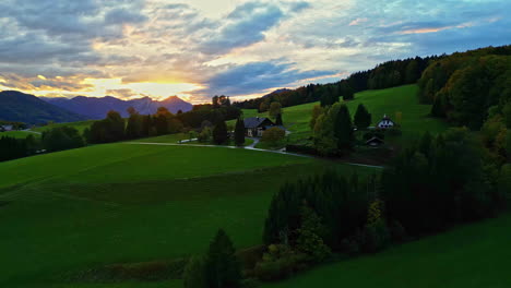 Picturesque-home-in-rolling-grassy-green-hills-of-European-countryside-at-sunset