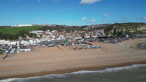 Aerial-drone-shot-of-Hastings-UK,-Wide-Tracking-shot-of-the-Land-Based-Fishing-Fleet-of-Beach,-Old-Town-and-East-Hill-Cliffs