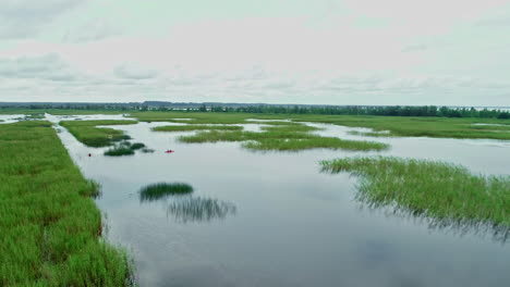 Überflutetes-Grasland-Oder-Ebenen-Spiegeln-Den-Bewölkten-Himmel-Darüber-Wider,-Luftrückzug