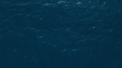 Glistening-sunlight-on-dark-deep-blue-ocean-water-in-a-therapeutic-zen-pattern,-aerial