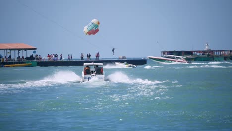 Local-and-foreign-tourists-paragliding-and-sailing-in-speedboats-at-the-beachfront-of-Pattaya,-in-the-Chonburi-province,-Thailand