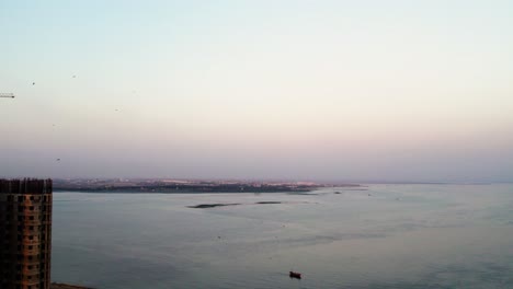 Sunset-reflection-over-coastal-cityscape-and-sea