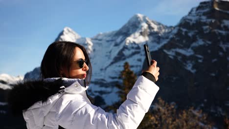 Inspired-female-tourist-in-Switzerland-take-photos-of-snowy-mountain-range