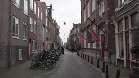 Street-in-Amsterdam-city-center-with-pakred-bicycles-and-flags-on-the-buildings