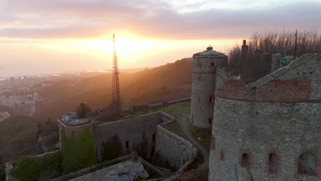 Forte-Sperone-Bei-Sonnenuntergang-Mit-Genua-Stadtbild-Im-Hintergrund,-Goldenes-Licht,-Luftaufnahme