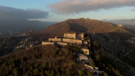 Forte-Sperone-at-sunset-with-surrounding-forest-and-mountains-in-Genoa,-Italy,-aerial-view