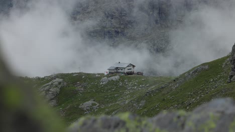 Incredible-scene-of-chalet-house-on-top-of-mountain-hill,-seen-through-rocks