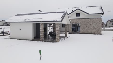 Aerial-of-modern-smart-home-covered-in-snow-with-solar-panel-installed-on-rooftop-house-in-residential-districts,-Power-outage-blackout-and-snowstorm-winter-season-concept