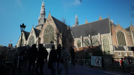 Personas-Frente-Al-Edificio-Más-Antiguo-De-La-Oude-Kerk-Amsterdam-En-Ámsterdam,-Países-Bajos