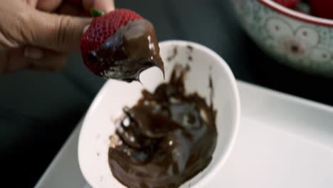 Dipping-strawberries-in-melted-chocolate-fondue-inside-a-white-dish-for-valentine's-day