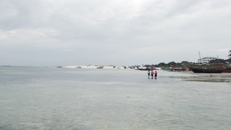 Sandy-beach,-ocean-and-wooden-boats-in-zanzibar-at-cloudy-day,-tanzania