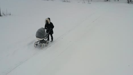 Single-mother-walk-with-newborn-baby-in-carriage-during-winter-snowfall