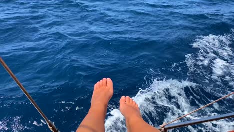 Frauenfüße-Auf-Einem-Segelboot-Und-Meereswellen,-Lustiger-Sommerurlaub,-Fahrendes-Boot,-Sonniger-Urlaub,-4K-Aufnahme