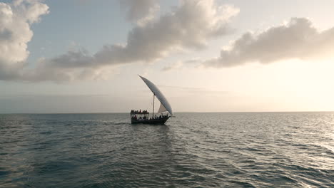Summer-concept,-dhow-boat-sails-in-the-ocean-at-sunset,-Zanzibar,-Tanzania