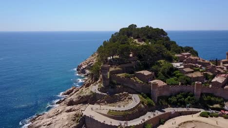 Flying-close-to-the-hill-with-a-castle,-on-the-rocky-coastline-of-the-Mediterranean-Sea